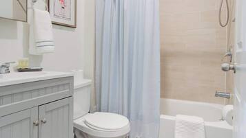 Comfort studio | Badkamer | Een bad/douchecombinatie, een haardroger, handdoeken, zeep