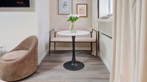 Une petite pièce agréable et chaleureuse, avec une table ronde, un fauteuil confortable, un téléviseur à écran plat et des tableaux encadrés accrochés au mur.