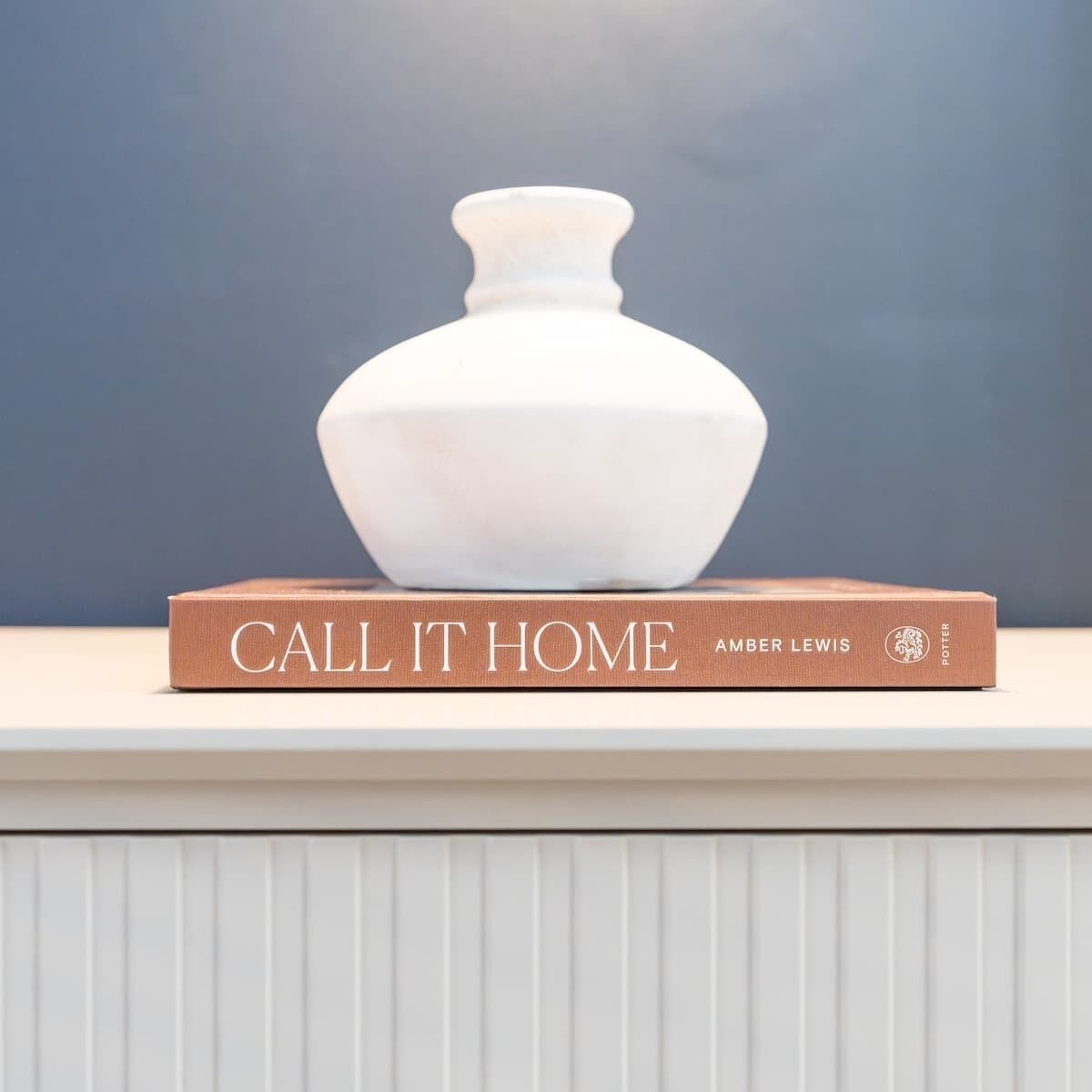 Eine weiße Vase auf einem Buch mit dem Titel 'Call It Home' von Amber Lewis.