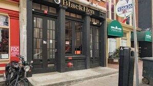 Un bâtiment sur lequel on peut lire l’inscription « BlackHen », avec une moto garée devant.