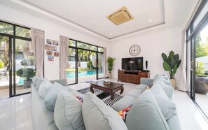 A modern living room with a large sofa, a coffee table, and a TV. - Villa Lotus Heaven -Private 4BR Pool Villa. Phuket, Laguna area (Tambon Choeng Thale)