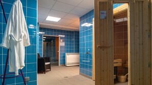 Ein Badezimmer mit blauen Fliesen, einer hölzernen Saunatür, einem weißen Handtuch an einem Wäscheständer und einem schwarzen Stuhl.