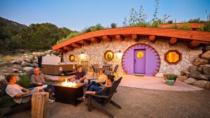 Un edificio de piedra con una puerta morada, mesas al aire libre y un brasero.