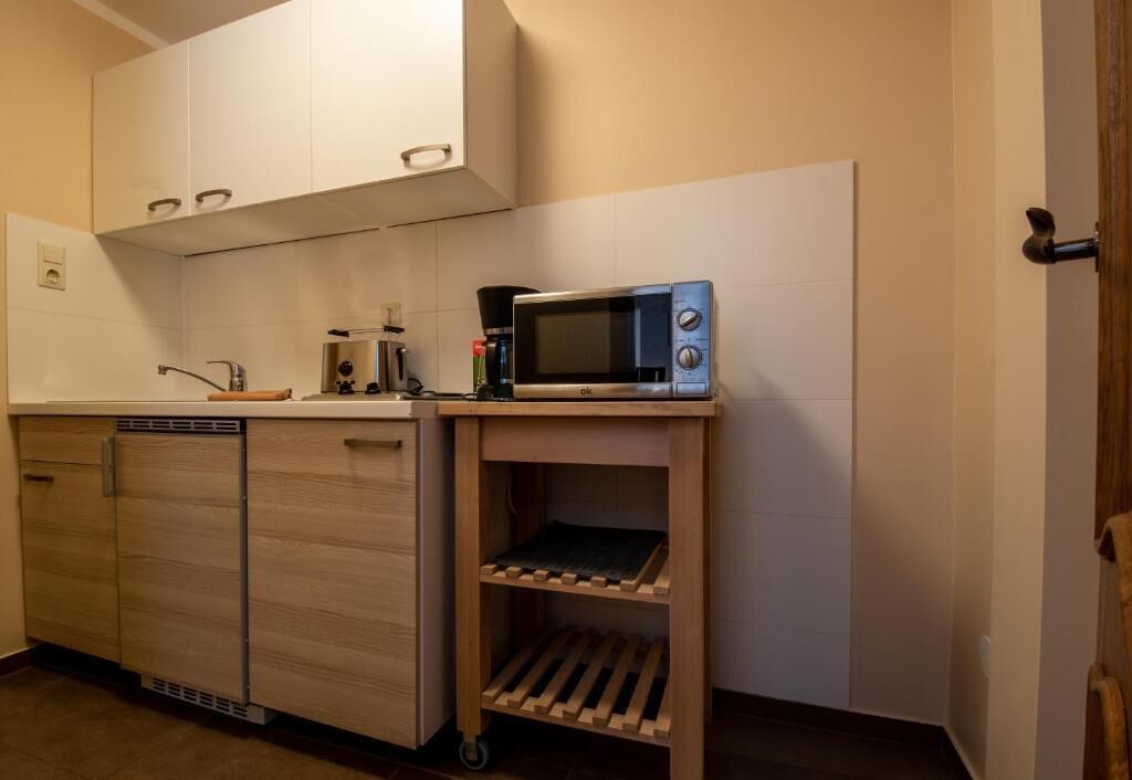 A compact kitchen with a microwave, a coffee maker, and a wooden cabinet.