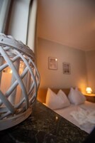 Una habitación de hotel con una cama, una mesita de noche, una lámpara y un objeto decorativo de metal sobre el mostrador.