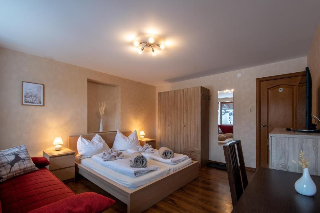 Une chambre à coucher avec un lit, des tables de chevet, un canapé rouge, une table à manger et un vase.