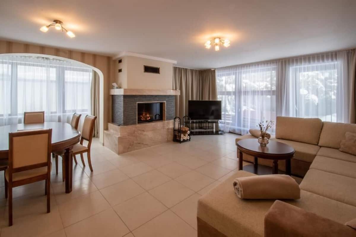 A living room with a fireplace, a TV, a dining area, and a sofa.