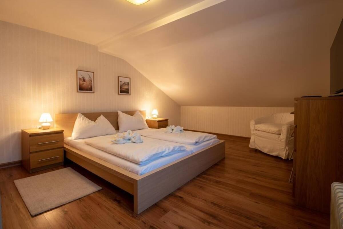 A bedroom with a wooden bed, bedside lamps, a chair, and a nightstand.