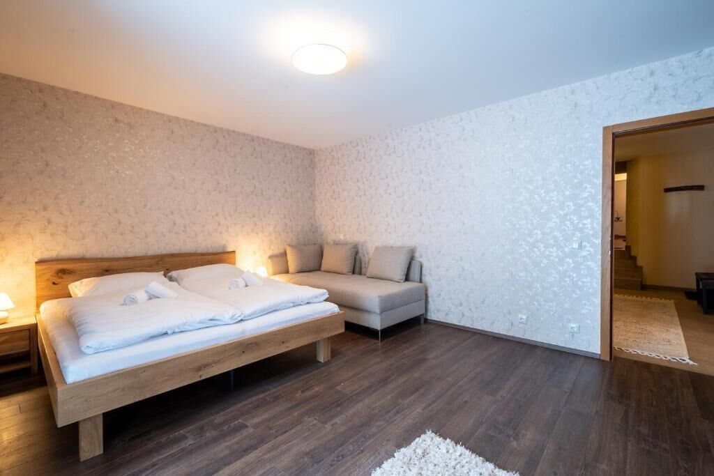 A bedroom with a bed, a sofa, a nightstand, and a wall with a textured pattern.