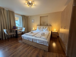 Una habitación de hotel con una cama grande, un escritorio, una silla, un armario y una ventana con cortinas.
