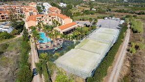 Vista aérea de un resort con piscina, canchas de tenis y zona de estacionamiento.