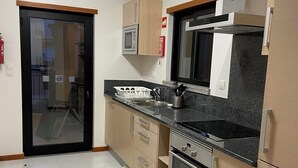 Una cucina moderna con elettrodomestici in acciaio inossidabile, mobili impiallacciati in legno e un piano di lavoro nero.