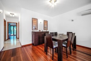 Un área de comedor con una mesa y sillas de madera, un mueble de color oscuro y obras de arte enmarcadas en las paredes.