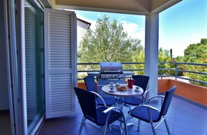 A balcony with a grill, chairs, and a table with food and drinks. - Equipped Flat Just a Short Walk From the Beach (Novigrad)