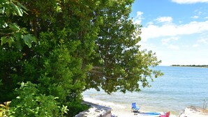 Una spiaggia con un muro di pietra, una sedia blu e un kayak.