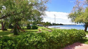 Un parco con giochi per bambini, specchi d'acqua e un gazebo.