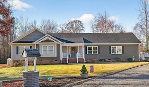 A single-story house with a front porch, a small front yard, and a gravel driveway.