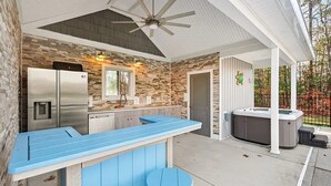 A covered outdoor kitchen area with a built-in refrigerator, a bar counter, and a hot tub. - Olivet Oasis - saltwater pool, hot tub, pond, walking trails, game room (New Kent)