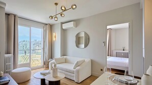 A modern living room with a white sofa, a round mirror, and a dining table set with glasses and plates. - Charming Apartment in Beaubourg - Le Marais (Paris)