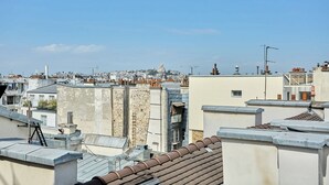 A cityscape with multiple rooftops, some with visible chimneys and antennas, and a clear sky. - Charming Apartment in Beaubourg - Le Marais (Paris)