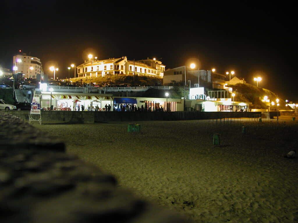 A beachfront hotel with a large building, multiple balconies, and a sandy beach area.