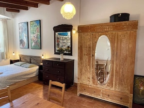 Ein Schlafzimmer mit Bett, Kommode, Schminktisch und einem großen Spiegel.