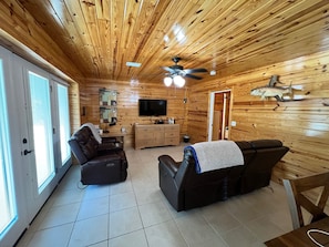 A wooden cabin interior with a TV, leather sofa, and a fish decoration on the wall. - 2-bedroom house in peaceful Perdido Beach with AC comfort (Perdido Beach)