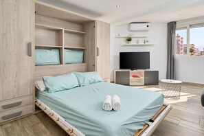 Une chambre d’hôtel moderne équipée d’un lit, d’une armoire intégrée, d’une télévision et offrant une vue sur la ville.