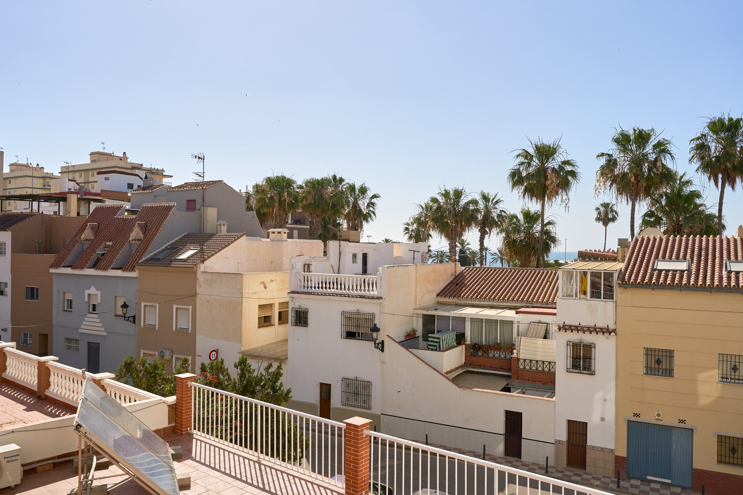 A residential area with multi-story buildings, balconies, and palm trees.
