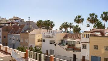 A residential area with multi-story buildings, balconies, and palm trees.