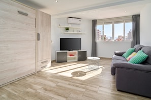 Uma sala de estar moderna com sofá, TV e vista para a cidade.