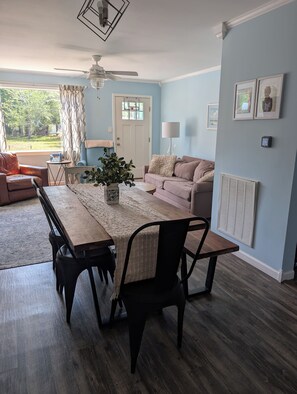 A dining area with a wooden table, chairs, and a vase of flowers. - Coastal Comfort Pet Friendly Beach Getaway Close to the Beach! Sleeps 6 (Supply)