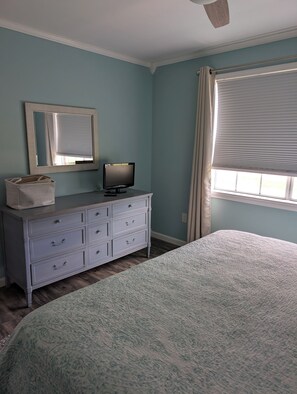 A bedroom with a bed, a dresser, a television, a window with blinds, and a ceiling fan. - Coastal Comfort Pet Friendly Beach Getaway Close to the Beach! Sleeps 6 (Supply)