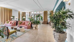 A spacious lobby with a high ceiling, plush seating, and large potted plants. - Bright Open Wynwood 1BR · Balcony + Rooftop Pool (Miami)