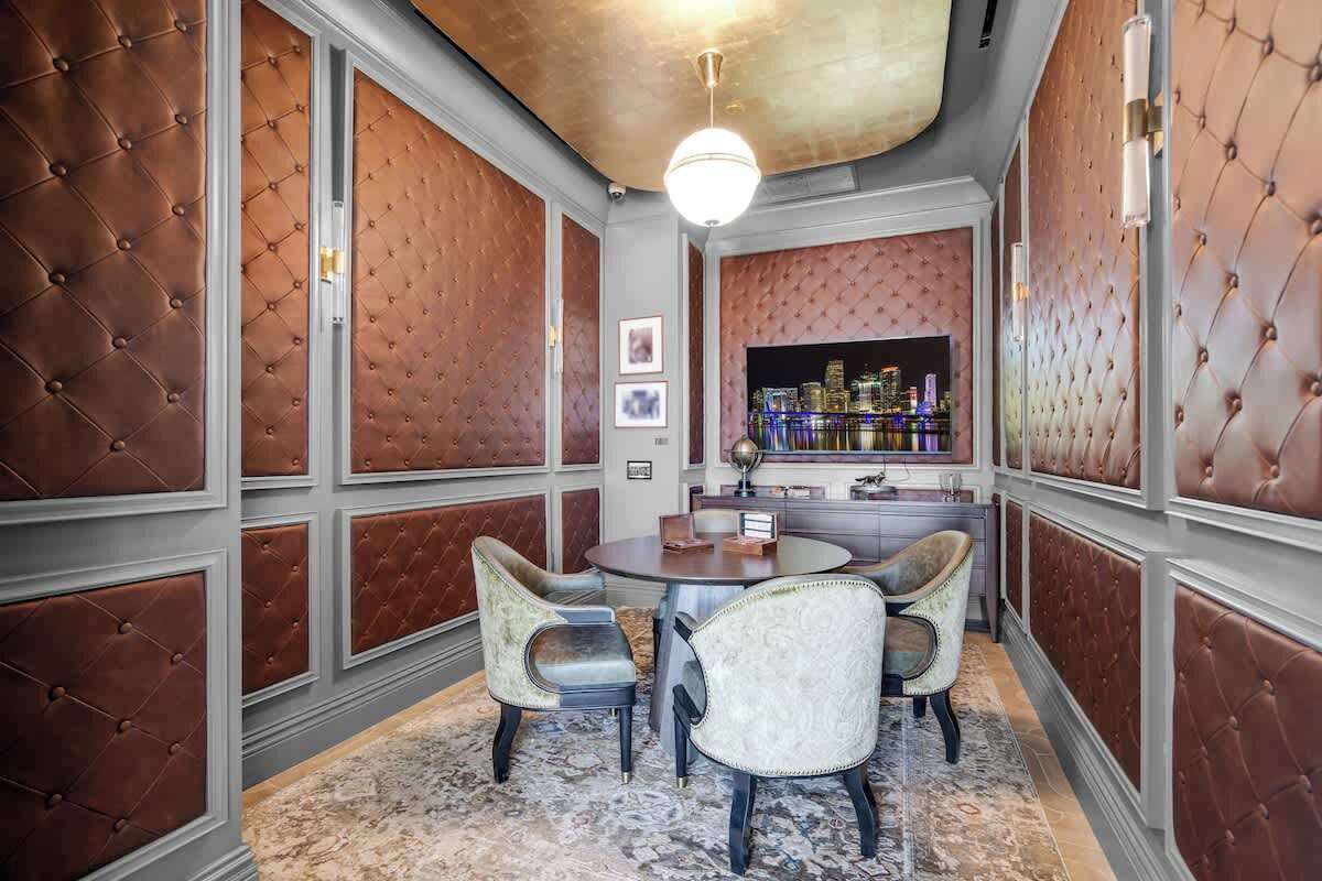 A room with a round table, four chairs, a cityscape view, and a bar area.