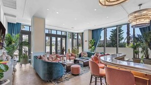 A spacious living area with a bar, seating, and large windows. - Bright Open Wynwood 1BR · Balcony + Rooftop Pool (Miami)