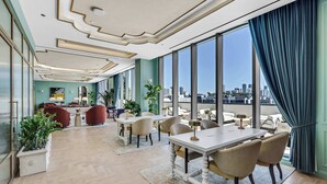 Eine geräumige Hotelhalle mit hoher Decke, großen Fenstern und Blick auf die Skyline der Stadt.