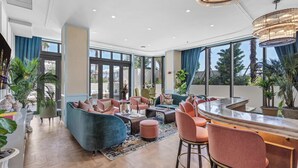 Eine moderne Hotelhalle mit einer gebogenen Bar, Sitzbereichen und großen Fenstern.