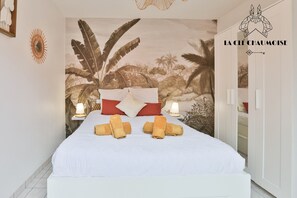 A bedroom with a large bed, two bedside lamps, a tropical mural, and a wardrobe. - L’Oasis Sablaise Patio terracotta, calme, 4 pers, proche plage centre (Les Sables-d´Olonne)