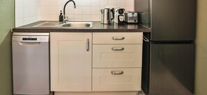 A compact kitchen with a dishwasher, stainless steel appliances, and a refrigerator. - L’Oasis Sablaise Patio terracotta, calme, 4 pers, proche plage centre (Les Sables-d´Olonne)