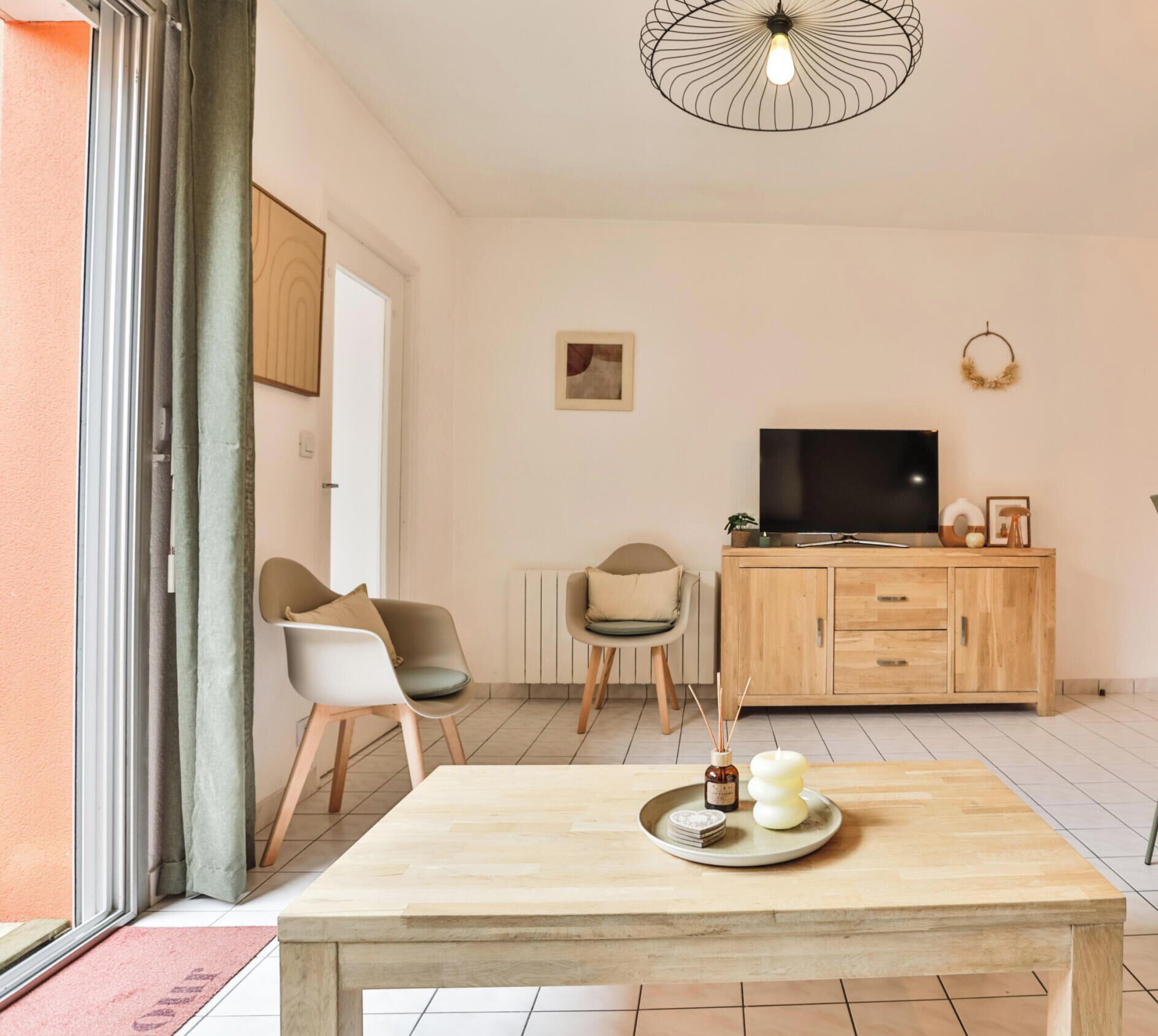 A modern living room with a wooden table, two chairs, a TV, and a cabinet.