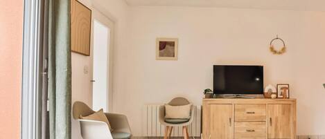 A modern living room with a wooden table, two chairs, a TV, and a cabinet.