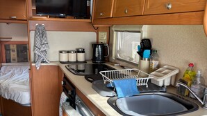 Een kleine RV keuken met een spoelbak, fornuis en magnetron.