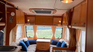 Een gezellig interieur van een camper, met een kitchenette, een eethoek en een slaapvertrek.