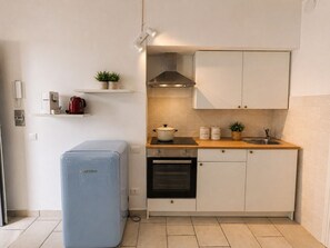 A compact kitchen with white cabinets, a small countertop, a stove, a sink, and a blue refrigerator. - Casa Marì by Theater Home - with balcony (Toscolano-Maderno)