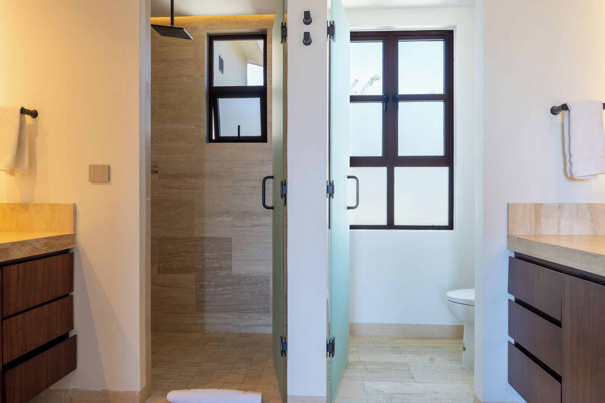 Une salle de bain moderne avec une douche à parois de verre, des toilettes et des meubles en bois.