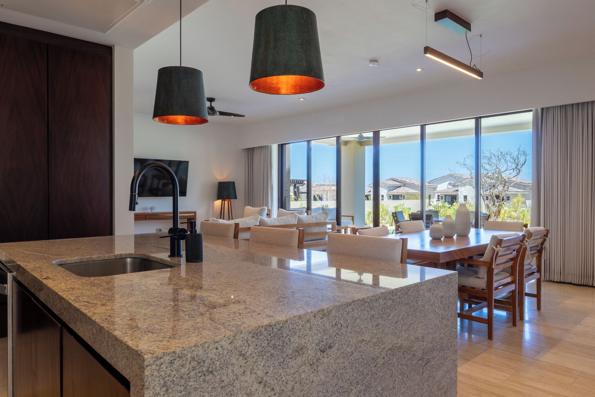 Une cuisine moderne dotée de plans de travail en granit, d’un évier encastré et de luminaires suspendus.