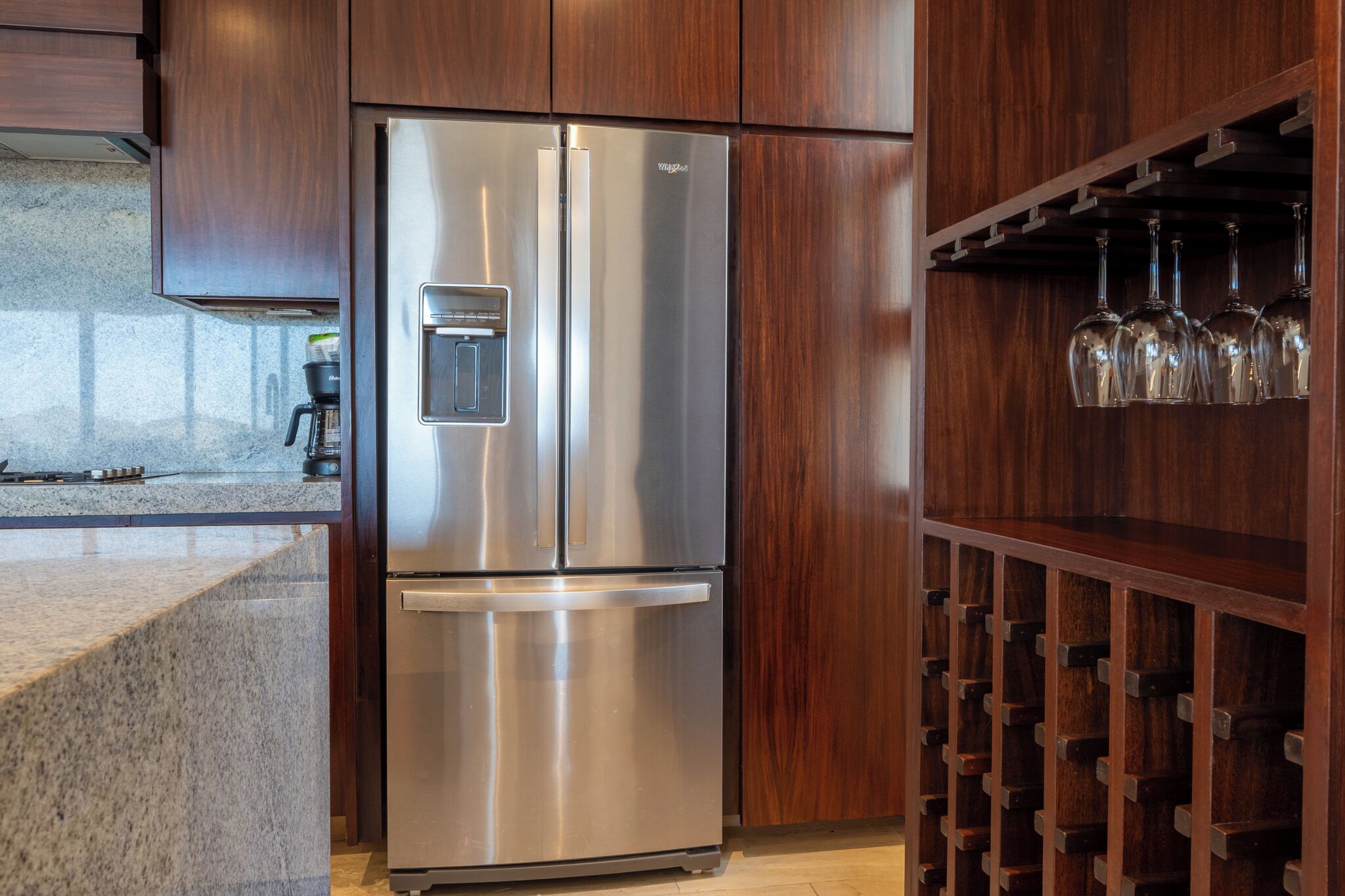 A stainless steel refrigerator with a freezer compartment, a built-in ice maker, and a wine rack with multiple bottles.