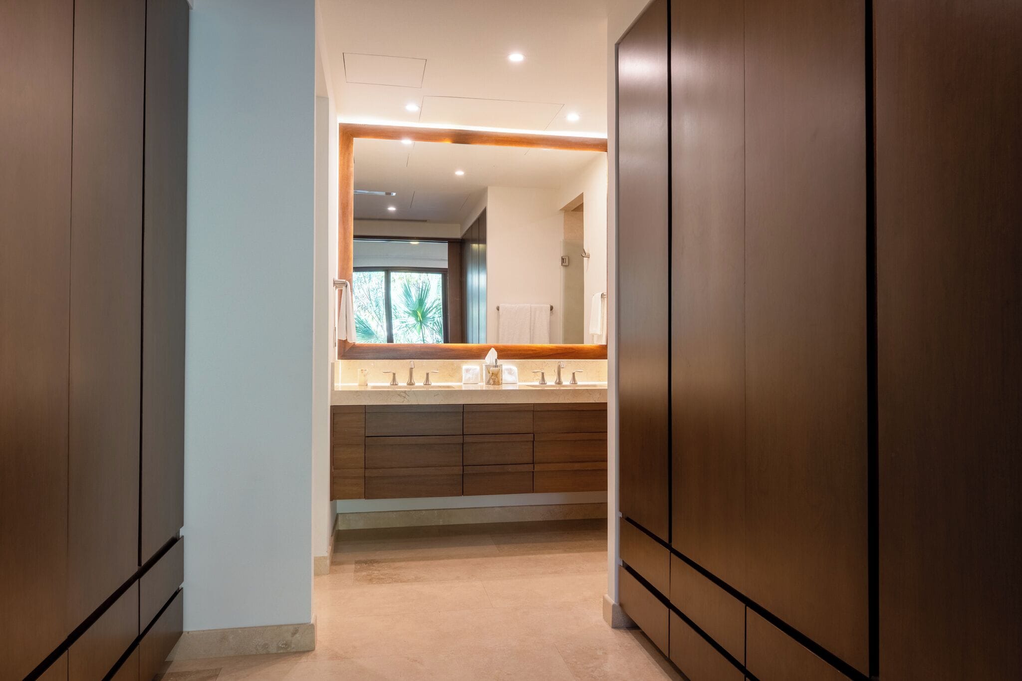 A modern bathroom with a large mirror, a vanity with a countertop, and a shower area.