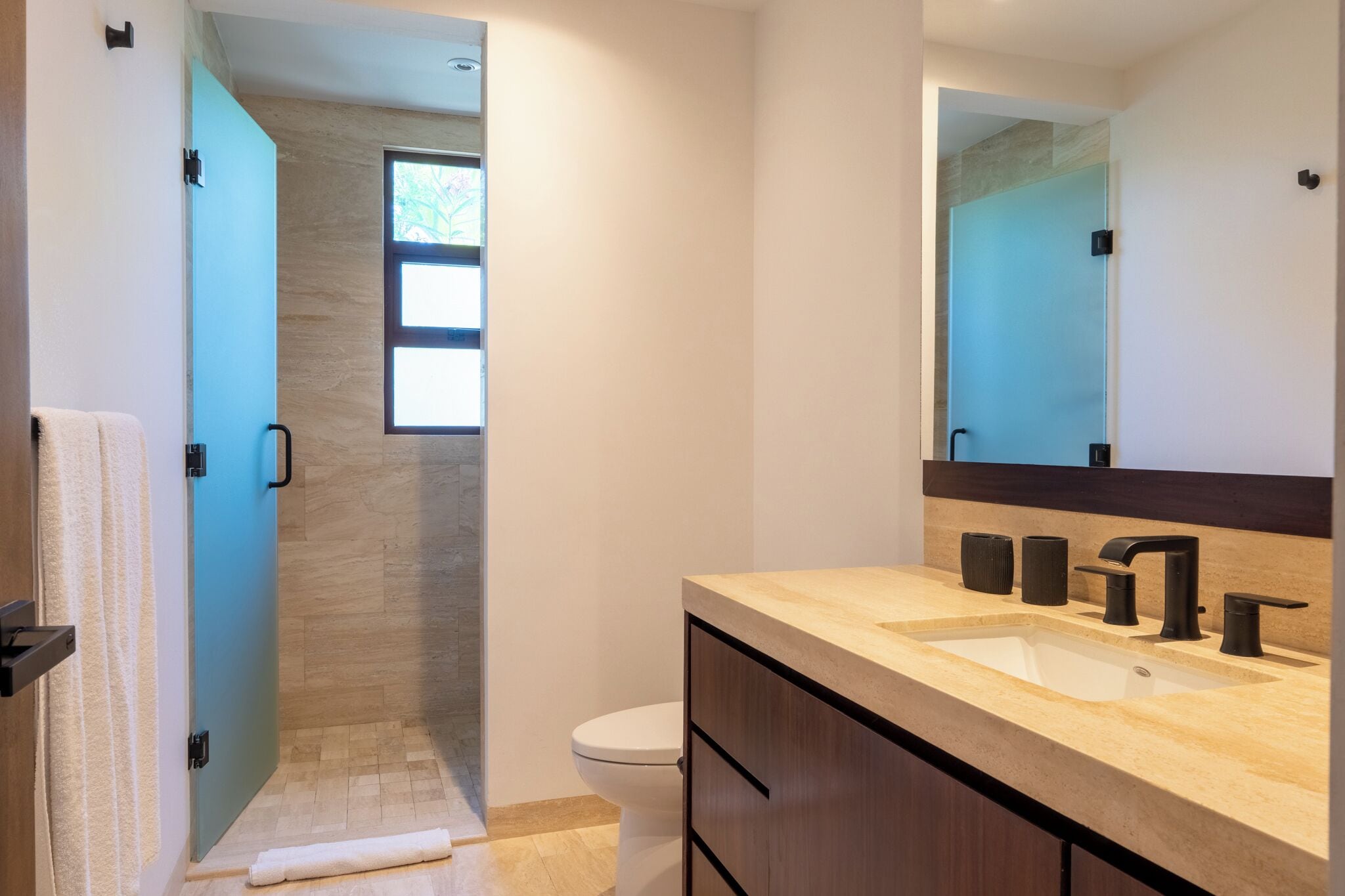 A modern bathroom with a shower, toilet, and vanity with a sink and mirror.